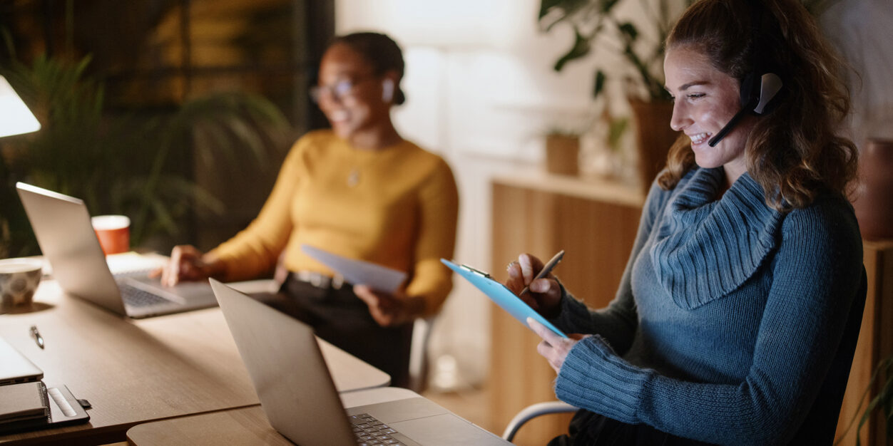 Ambitious and confident businesswomen using laptop computer. Professional people late at night working in small office