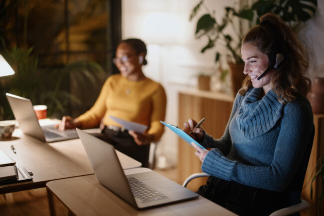 Ambitious and confident businesswomen using laptop computer. Professional people late at night working in small office