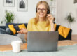 Smiling female call center employee using a headset and laptop for online communication with customers, a woman talking into microphone and gesturing